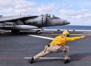 Um Marinheiro Sinaliza para um Harrier AV-8B