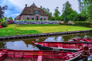 Giethoorn, Netherlands - July 6, 2019: Red Boats Docked In the Canal In Front of A Typical Dutch Rural House In the Village of G