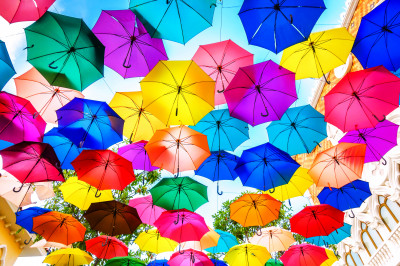 Guarda-chuvas multicoloridos flutuando acima da rua